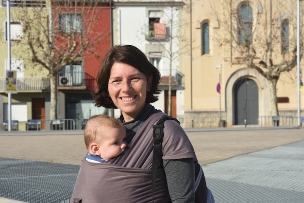 Foto retrato de una mujer que llevaba a su hijo en un entorno urbano