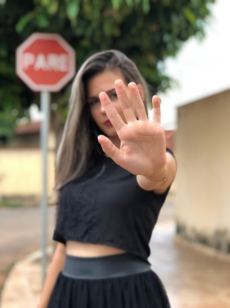 Foto retrato de una mujer que muestra una señal de parada mientras está de pie en la carretera