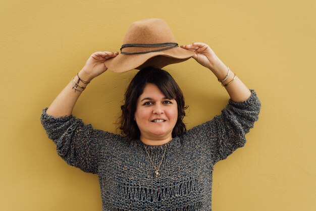 Retrato de una mujer que sonríe mientras sostiene un sombrero en la cabeza Street fashion