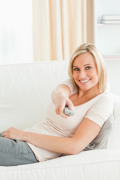 Retrato de una mujer que usa un control remoto con una sonrisa de complicidad