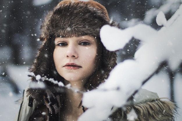 Retrato de una mujer por una rama nevada durante la nevada