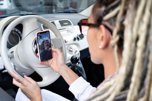 Retrato de mujer rasta en un coche con videollamada con su amigo masculino