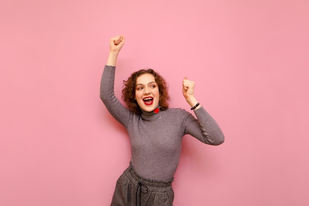 Retrato de mujer rizada alegre en ropa gris bailando