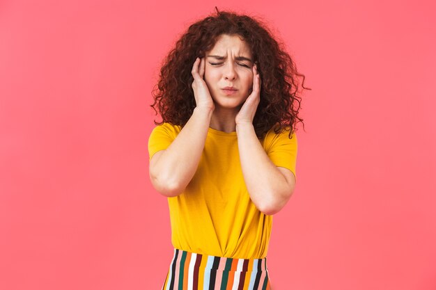 Foto retrato de una mujer rizada joven hermosa disgustada posando aislada en la pared roja coning orejas.