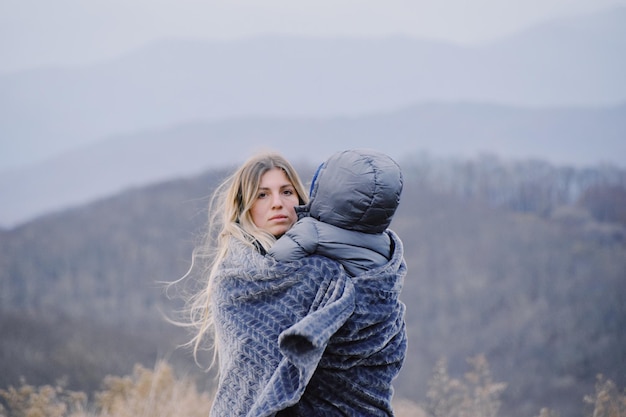 Retrato de una mujer con ropa cálida contra las montañas