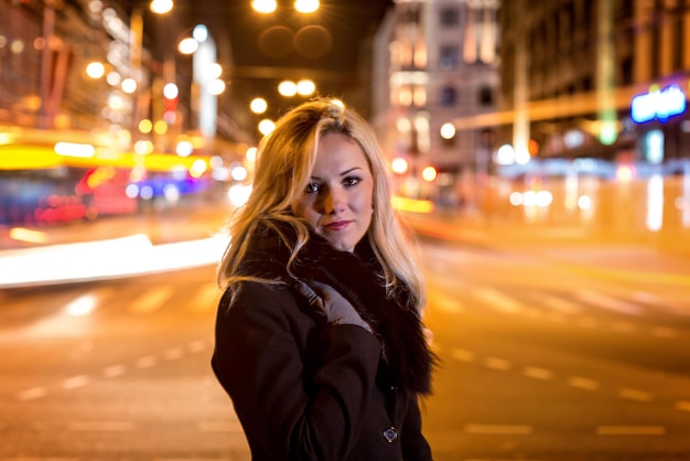 Foto retrato de una mujer con ropa cálida mientras está de pie en la calle por la noche