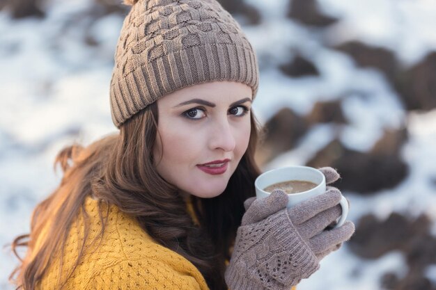 Retrato de una mujer con ropa cálida tomando café al aire libre