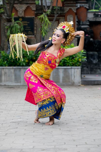 Foto retrato de una mujer con ropa tradicional bailando contra una estructura construida.