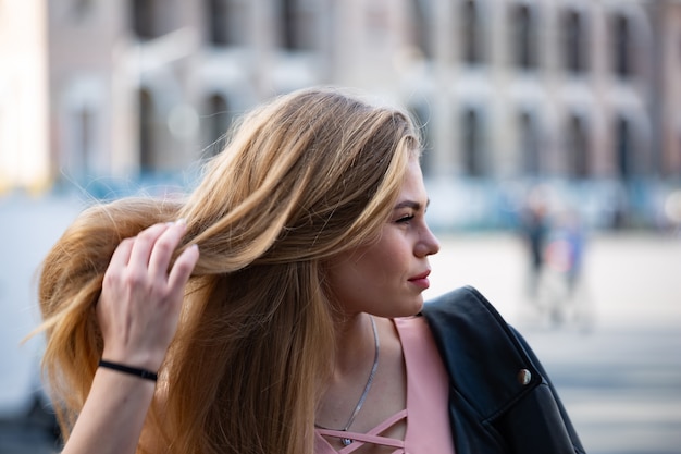 Retrato de mujer rubia joven feliz en gafas de sol con pelo largo