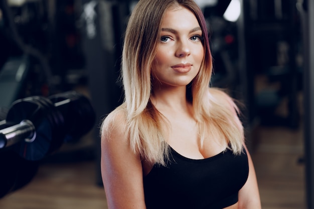 Retrato de una mujer rubia joven en forma en sujetador deportivo negro