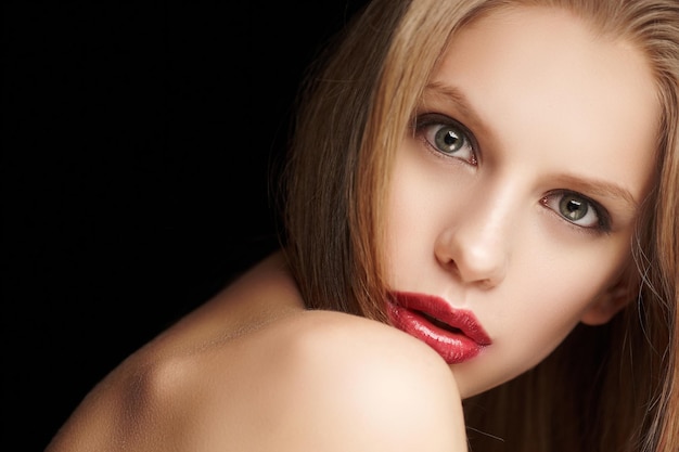 Retrato de mujer rubia con labios rojos aislado sobre fondo negro.