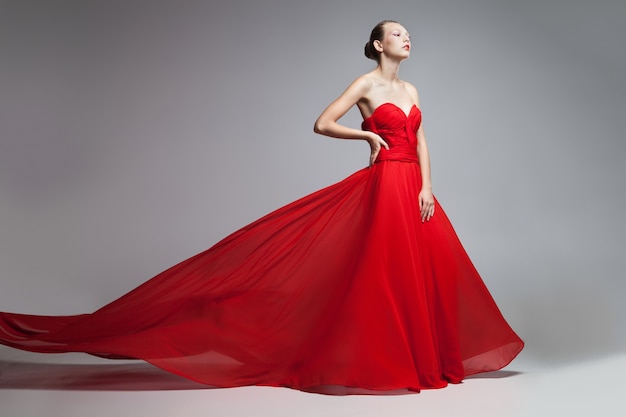 Retrato de mujer rubia con peinado en vestido rojo brillante con falda voladora