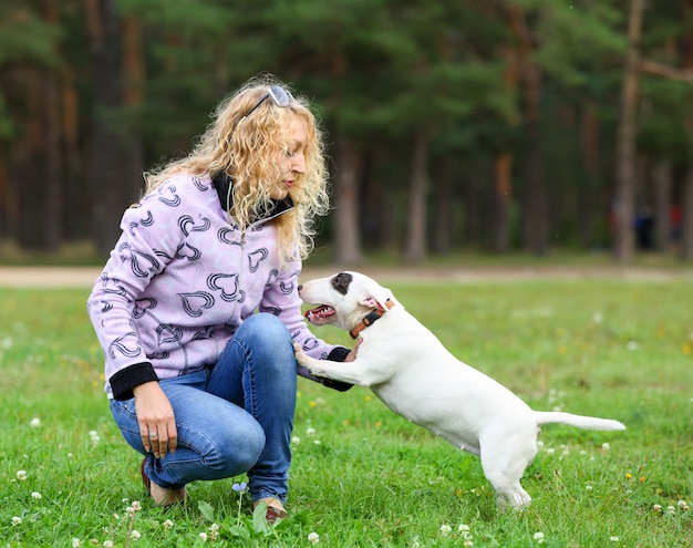 Retrato de una mujer rubia con un perro en el parque