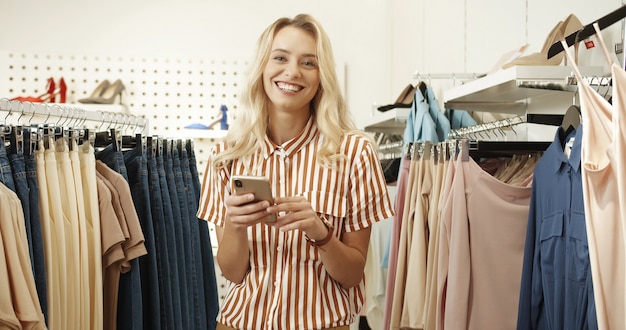 Retrato de una mujer rubia de pie en una tienda de ropa