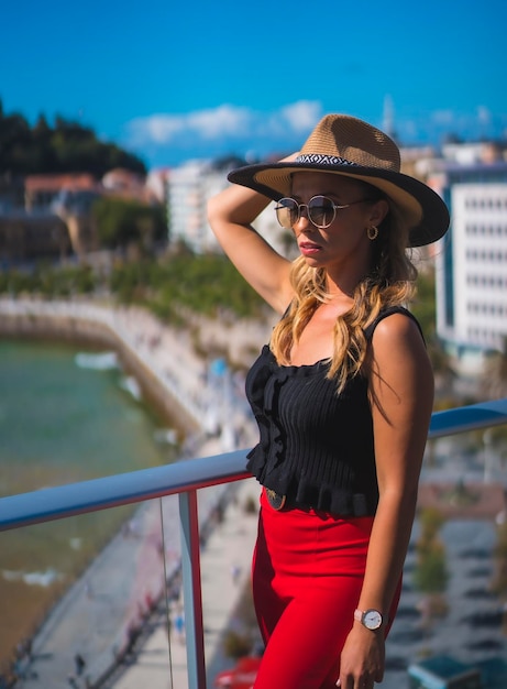 Retrato de una mujer rubia que pasa sus vacaciones en un hotel de lujo en una terraza con sombrero
