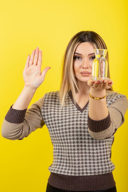 Retrato de mujer rubia con vaso de agua en amarillo.
