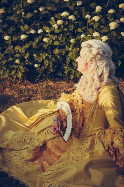 Retrato de mujer rubia vestida con ropa barroca histórica con peinado de moda antigua, al aire libre. Lujoso vestido medieval