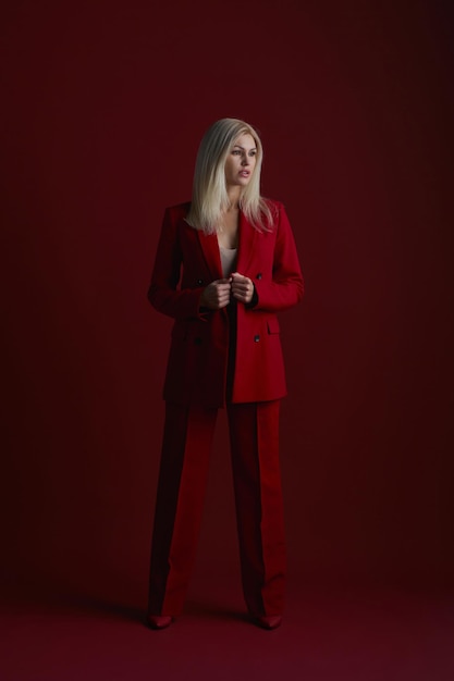 Retrato de una mujer rubia en vestido rojo sobre un fondo rojo.