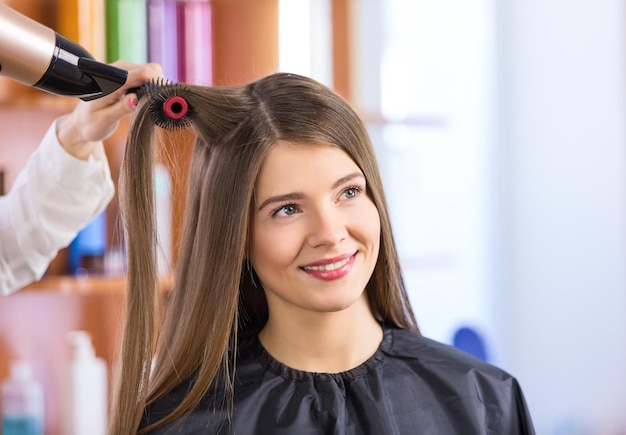 Retrato de mujer secándose el cabello en el salón de belleza