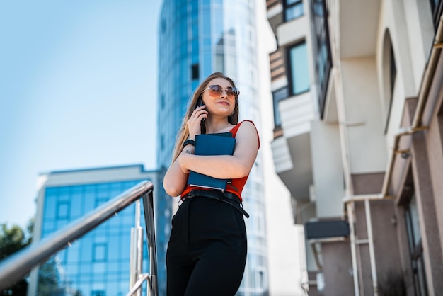 Retrato de mujer segura de sí misma con ropa informal elegante y usando un teléfono inteligente en una calle de la ciudad