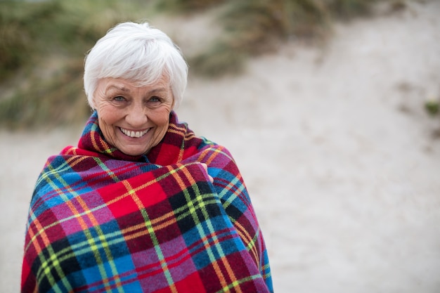 Retrato de mujer senior envuelta en un chal en la playa