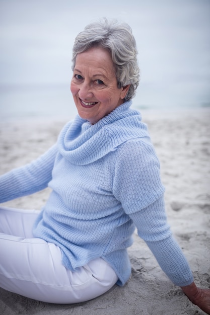 Retrato de mujer senior feliz sentada en la playa