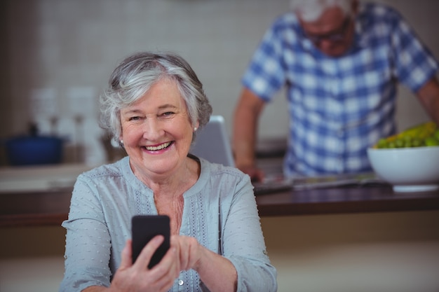 Foto retrato de mujer senior con teléfono en la cocina