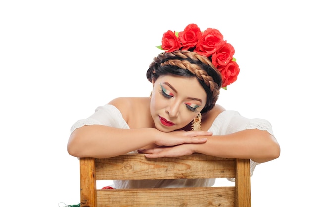 Retrato de mujer sentada con los ojos cerrados mostrando su maquillaje con los colores de la bandera de México.