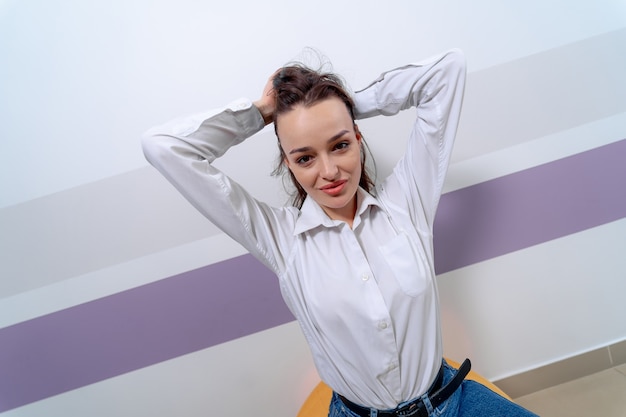 Retrato de una mujer sentada sobre una pelota de fitness naranja. Mujer con camisa blanca.