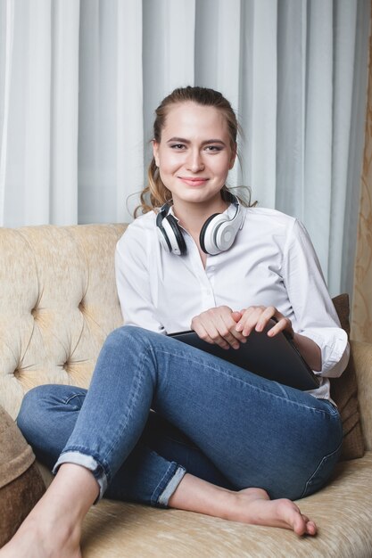 Retrato de mujer sentada en el sofá y escuchando música