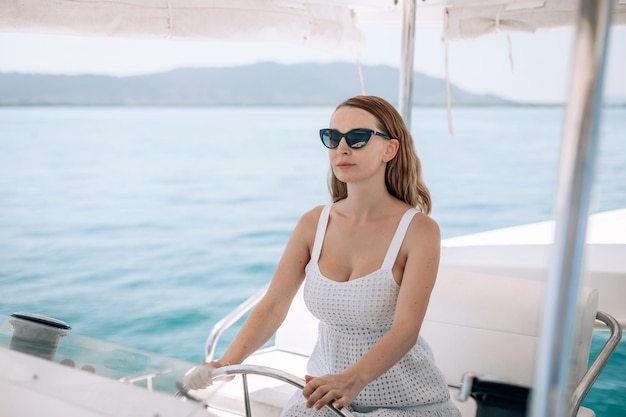 Retrato de una mujer seria y concentrada con un vestido blanco con escote abierto y gafas de sol