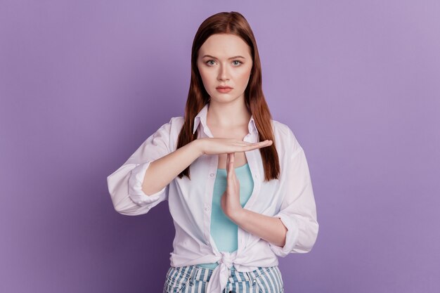 Retrato de mujer seria manos muestran signo de rotura sobre fondo púrpura