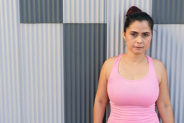 Retrato de mujer seria en ropa deportiva de pie en un parque.