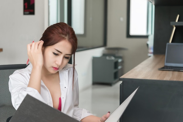 Retrato de mujer sexy asiática en la oficina. La gente de Tailandia se sienta en la silla para tomar una foto. Concepto de mujer de negocios sexy en una empresa.