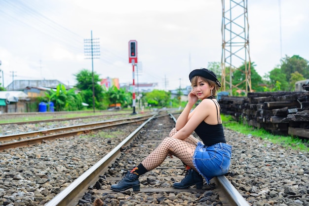 Retrato de mujer sexy asiática sentada en el ferrocarril para tomar una foto de estilo de pelo corto de mujer tailandesa