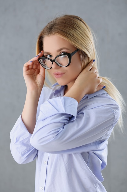 Retrato de una mujer sexy en la camisa de un hombre con gafas