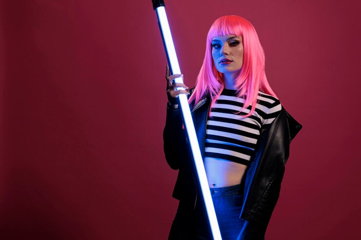 Foto retrato de mujer sexy posando con luz de neón fluorescente, sosteniendo luces de color púrpura violeta brillando en estudio oscuro. vistiendo una chaqueta de cuero de rockero frente a la cámara con iluminación futurista.