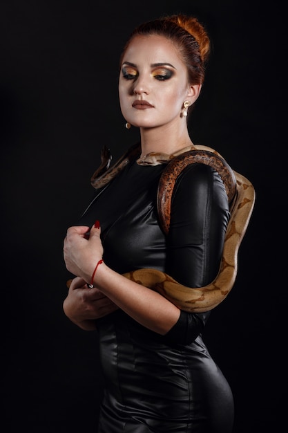 Retrato de mujer sexy con serpiente en traje de látex de cerca