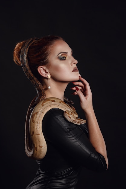 Retrato de mujer sexy con serpiente en traje de látex de cerca