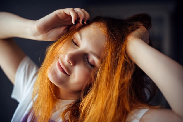 Retrato de mujer sexy sonriente tocando el pelo largo rojo. Modelo de mujer posando en el estudio, primer plano de la cara hermosa.