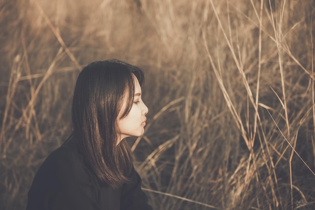 Retrato de una mujer solitaria sola en un campo. Estilo de filtro vintage. La angustia del concepto de chica lovesad en el estilo vintage de la puesta de sol.