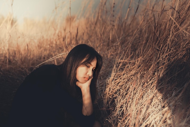 Retrato de una mujer solitaria sola en un campo. Estilo de filtro vintage. La angustia del concepto de chica lovesad en el estilo vintage de la puesta de sol.