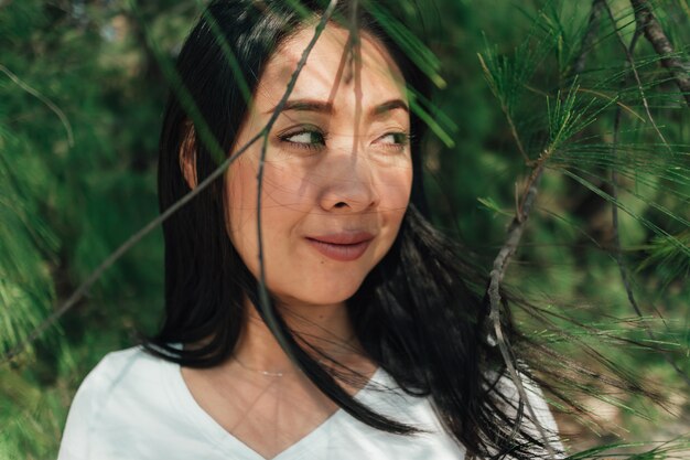 Retrato de mujer bajo la sombra de pino en verano.