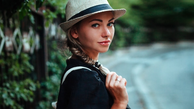 Retrato de una mujer con un sombrero con una mochila en la espalda