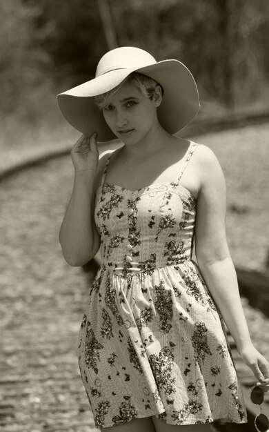 Retrato de una mujer con sombrero de sol en la vía del ferrocarril en un día soleado