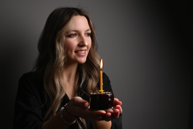 Retrato de mujer soñadora feliz cumpleaños celebrando el cumpleaños sonriendo y pidiendo deseos soplando velas en el pastel