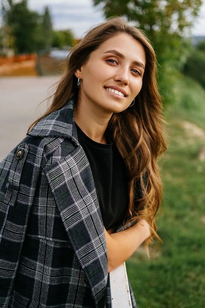 Retrato de una mujer sonriendo a la cámara de pie al aire libre en un día ventoso