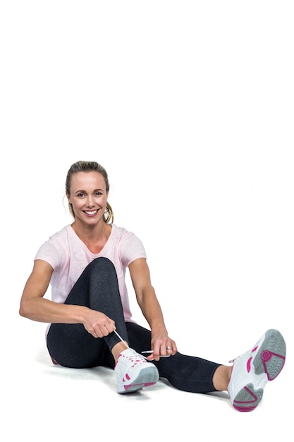 Retrato de mujer sonriendo mientras atar cordones de los zapatos