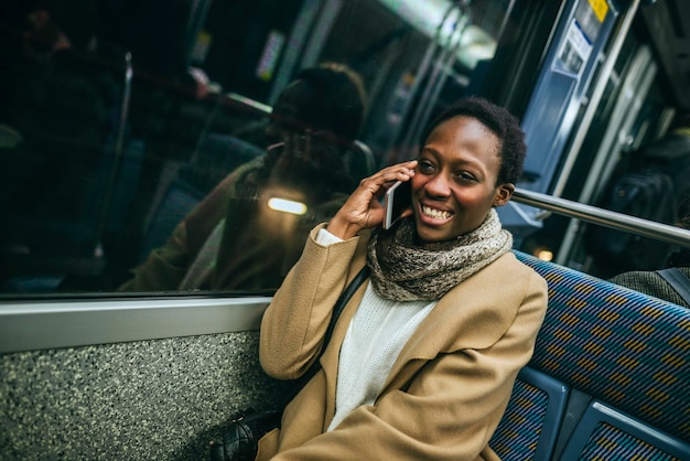 Retrato de mujer sonriente al teléfono en tren subterráneo