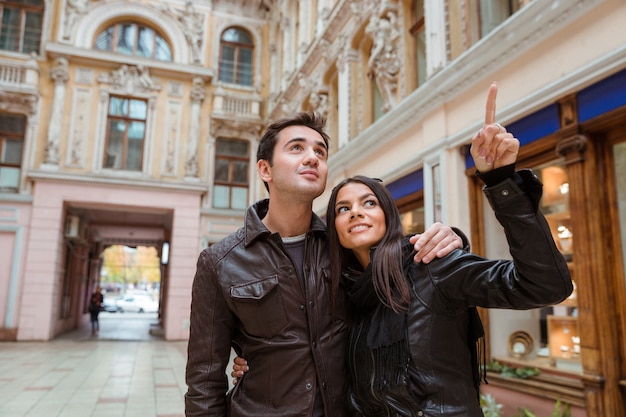 Retrato de una mujer sonriente apuntando con el dedo sobre algo a su novio al aire libre en la vieja ciudad europea